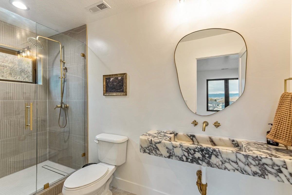 Attached Guest Bathroom Floating Marble Sink, Mirror, and Walk-in Shower in Bear Lake Custom Home by 10X Builders