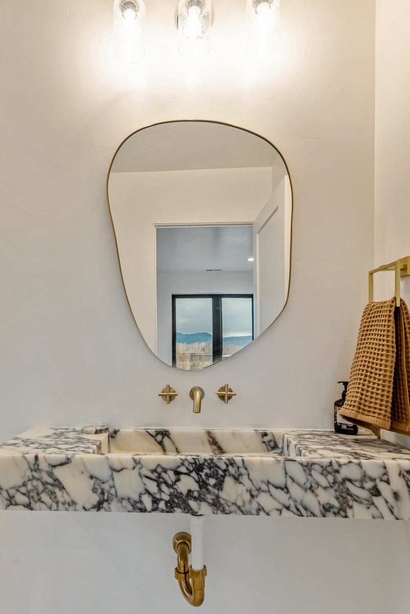 Attached Guest Bathroom with Floating Marble Sink and Abstract Mirror in Bear Lake Custom Home by 10X Builders