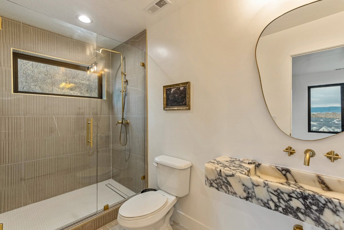 Attached Guest Bathroom with Floating Marbled Sink and Walk-in Shower with Window in Bear Lake Custom Home by 10X Builders