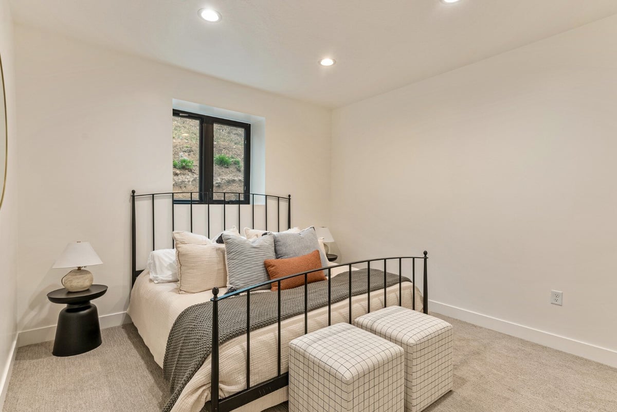 Bedroom with Metal Bed Framed Bed Under Window in Bear Lake Custom Home by 10X Builders