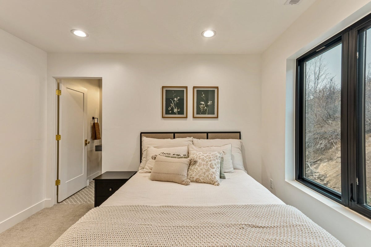 Guest Bedroom Bed with Small Window and Attached Bathroom in Bear Lake Custom Home by 10X Builders