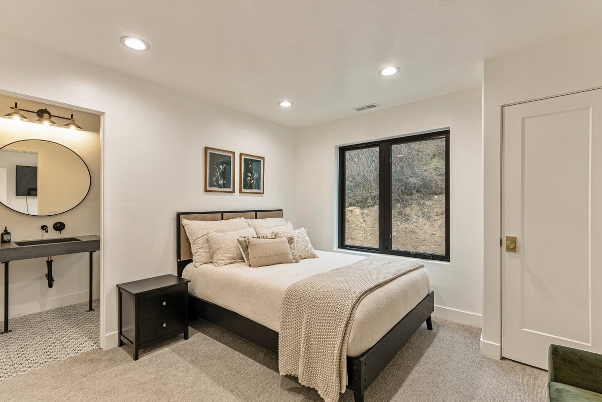 Guest Bedroom with Window, Nightstand, Closet, and Attached Bathroom in Bear Lake Custom Home by 10X Builders