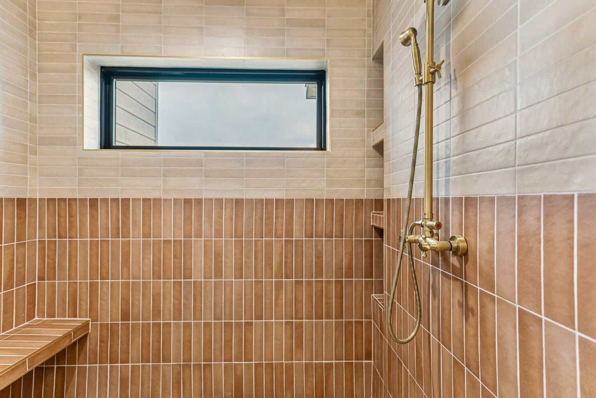 Inside the Master Bathroom Walk-in Shower with Attached Bench, Window and Tile Siding in Bear Lake Custom Home by 10X Builders