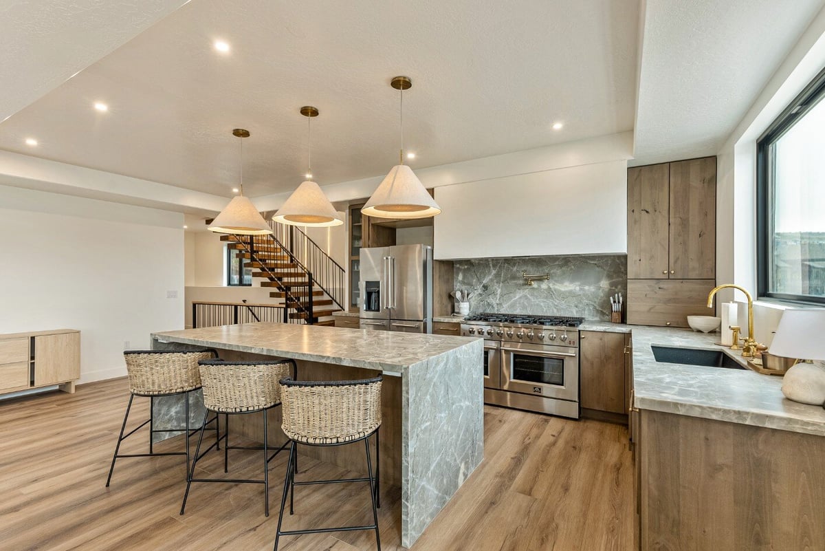 Kitchen Island with Barstools and View of Staircase in Bear Lake Custom Home by 10X Builders