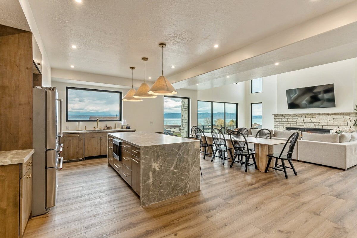 View From Kitchen and Dining Area into Living Room with Large Windows in Bear Lake Custom Home by 10X Builders